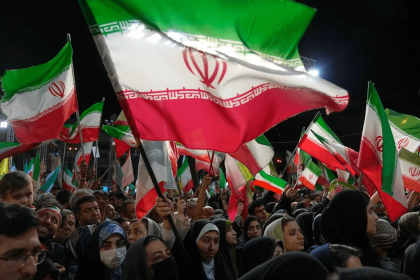 Warga Iran mengibarkan bendera Iran dalam demonstrasi di Lapangan Revolusi Islam di Teheran, Iran (AlMayadeen)